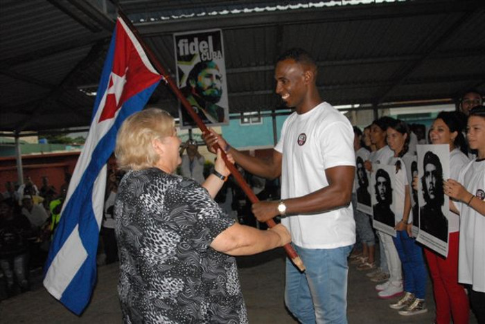 Richard Moré Molina, jefe del destacamento, recibió la Enseña Nacional de manos de Aleida Guevara. Foto: Otilio Rivero Delgado/ Adelante