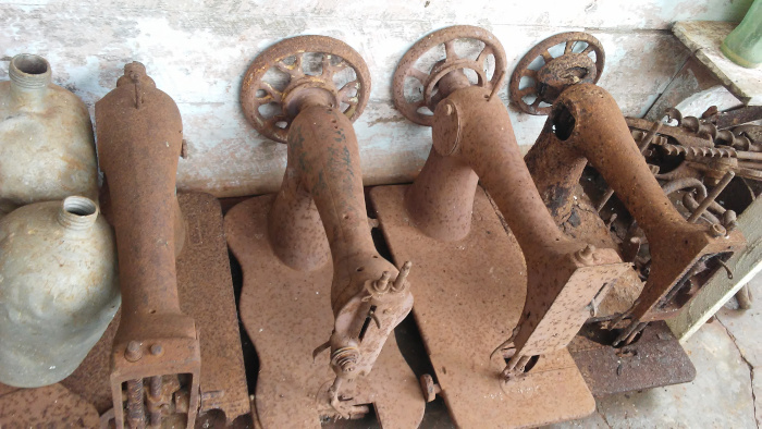Máquinas de coser de los siglos XIX y XX sufriendo la acción de la intemperie depositadas en el portal de la casa de Carlos.